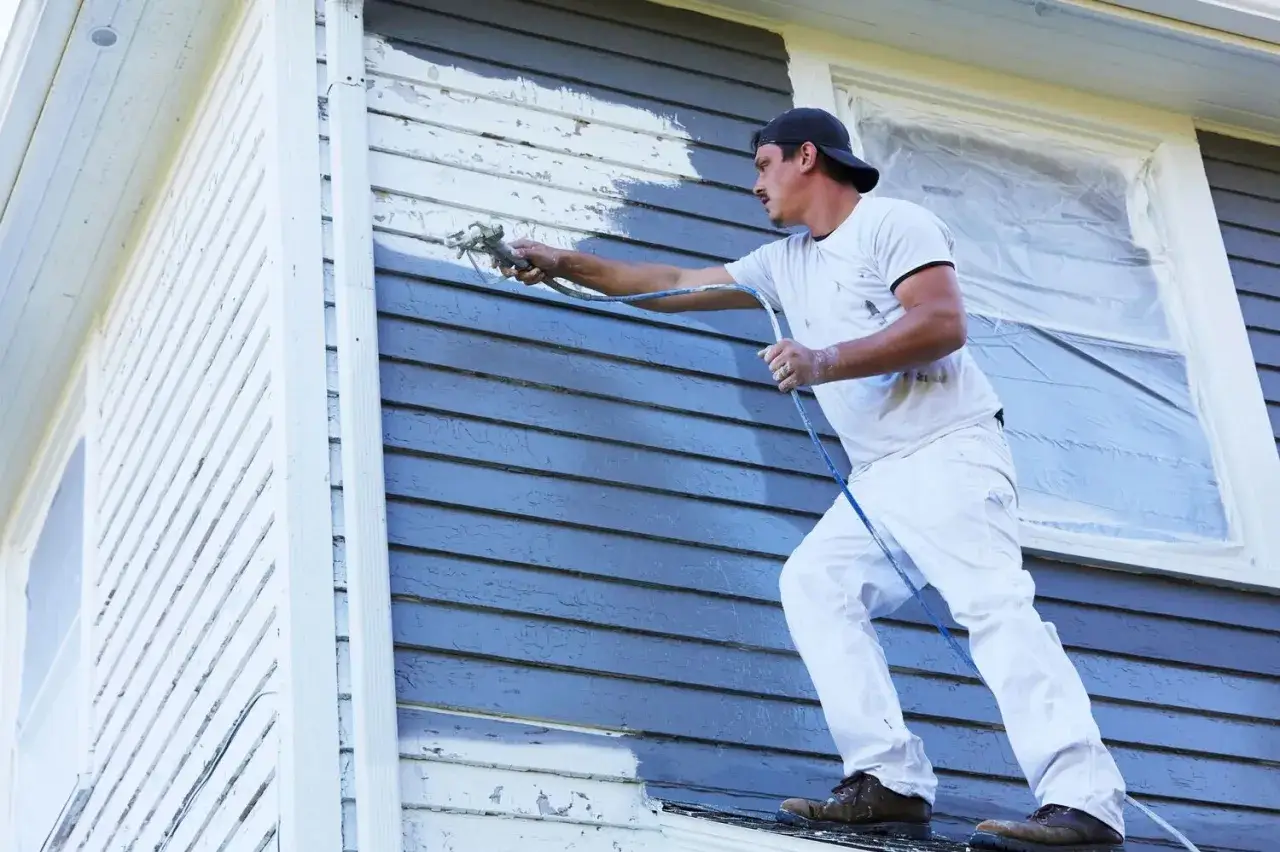 Pintor aplica imprimaci&oacute;n con pistola pulverizadora sobre la fachada de una casa. Se puede dar imprimaci&oacute;n encima de pintura vieja para renovarla.