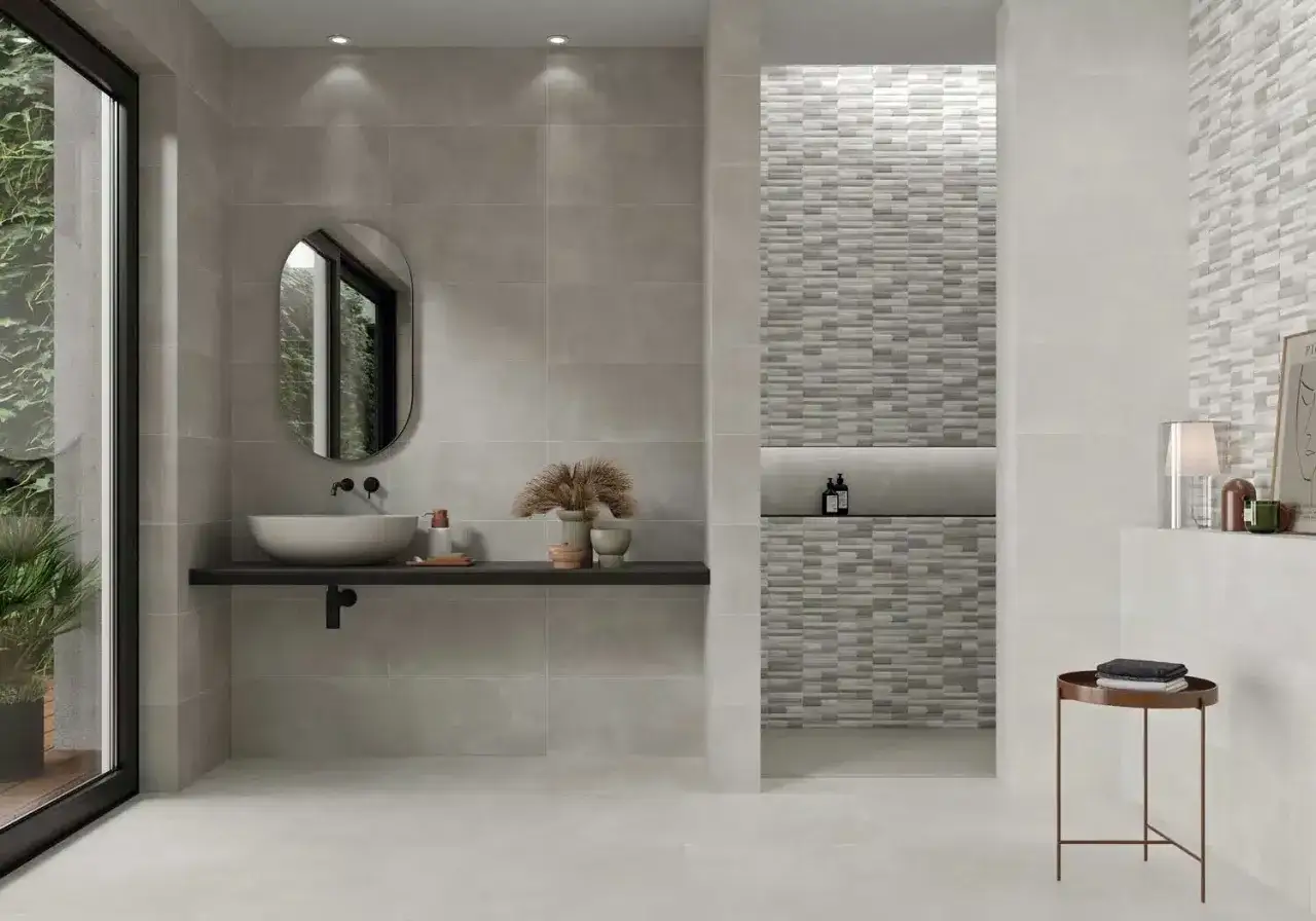 Ba&ntilde;o moderno con paredes y suelo de microcemento sobre azulejos, lavabo suspendido y ducha con mosaico texturizado.