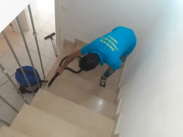 Un trabajador aspira escaleras para quitar polvo de obra.
