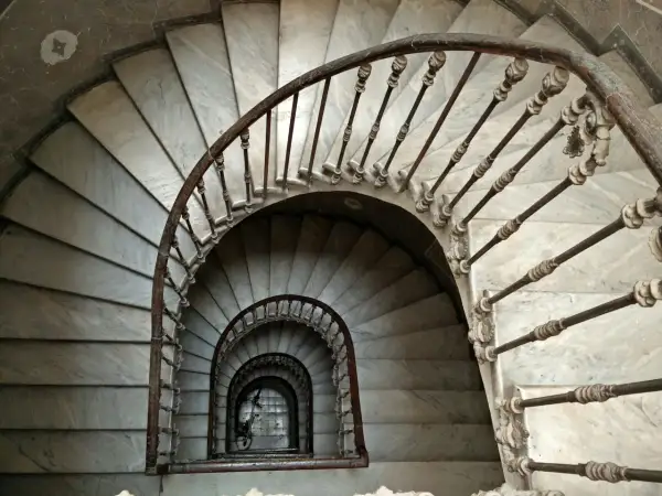 Escaleras de caracol de mármol con barandilla de hierro forjado. Un detalle de limpieza de escaleras de mármol revela su belleza clásica.