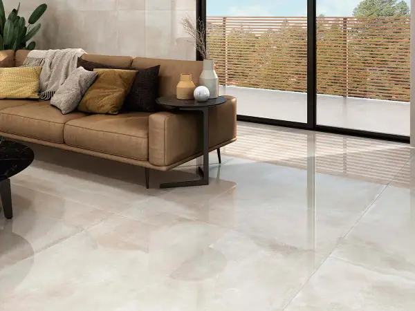 Elegante salón con sofá de cuero y suelo de gran formato, ideal para colocar baldosas.