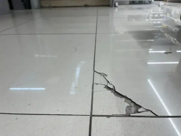 Baldosa rota en el suelo, con grietas y material desprendido. Una guía visual para saber como pegar una baldosa suelta.