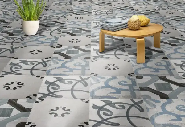 Un suelo hidráulico con un diseño de azulejos en tonos grises y azules, con un pequeño taburete de madera y una planta. ¡Perfecto para limpiar y lucir!